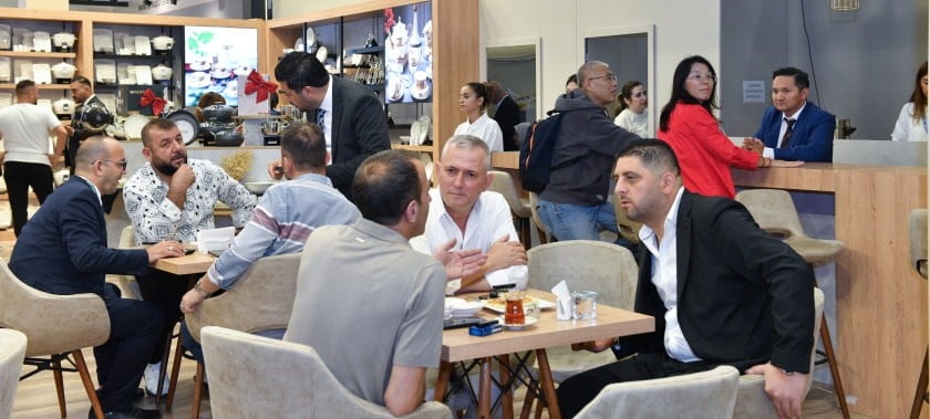 katılımcı ve ziyaretçi masada oturup sohbet ediyor